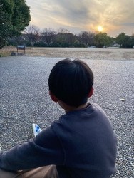 沈む太陽を眺める少年2022